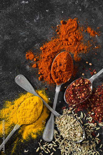Fototapeta Naklejka Na Ścianę i Meble -  Spices in metal spoons on a black table