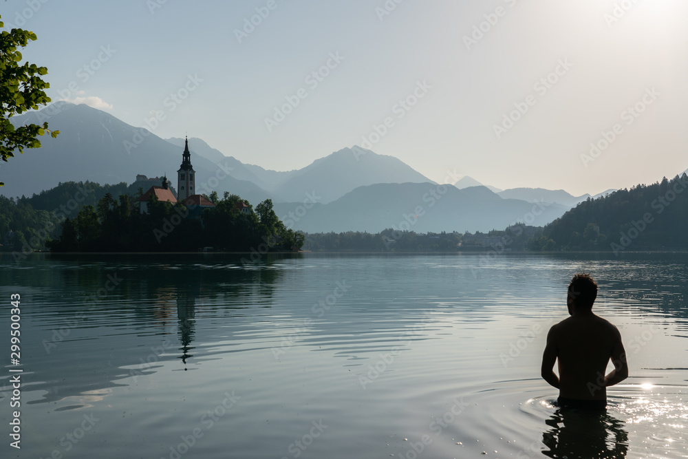 Silhouette of an European man bathing in lake Bled Silhouette of an European man bathing in lake Bled