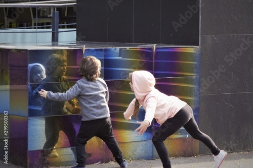 children play with reflection on mirror wall