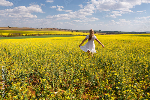 Foto Country girl frollicking in fields of golden canola