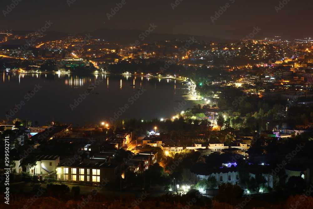 The view from the hill on the colorful panorama of the night Gulf of Gumbet suburb of Bodrum Turkey.Multi-colored neon lights,lamps,lights, night resort.Dawn fog.Reflection in water Wallpaper
