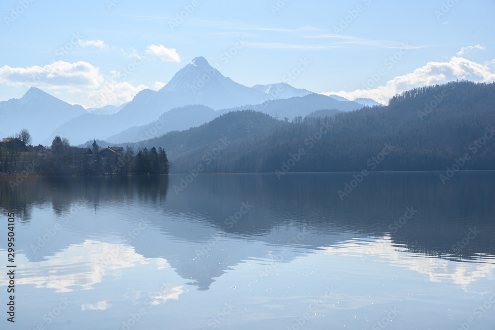 weissensee, idyllic lake in dusty morning light front of the blue mountains of the bavarian alps near füssen in the allgäu, germany, copy space