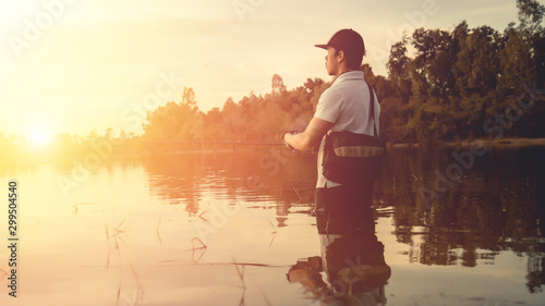 Man fishing in the lake at sunset.