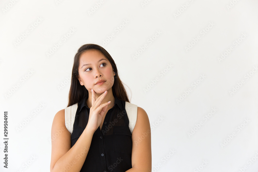 Pensive student girl touching chin and looking at copy space away. Young Latin woman in casual standing isolated over white background. Advertising concept Pensive student girl touching chin and looking at copy space away. Young Latin woman in casual standing isolated over white background. Advertising concept