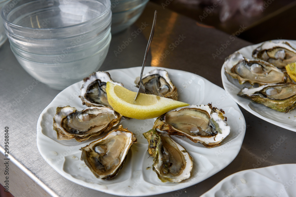 Oysters with lemon, served on white plate, ready for eat. Oysters from Bordeaux region. Oysters with lemon, served on white plate, ready for eat. Oysters from Bordeaux region.