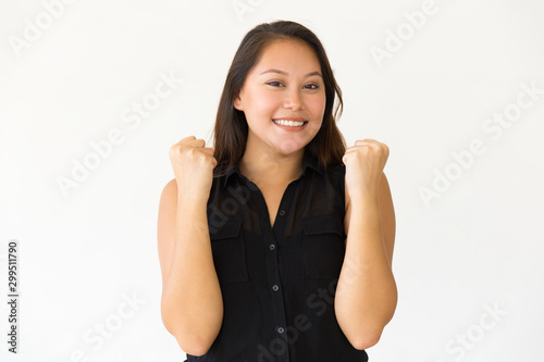 Happy young woman raising fists. Portrait of beautiful cheerful young woman celebrating and smiling at camera. Winner concept