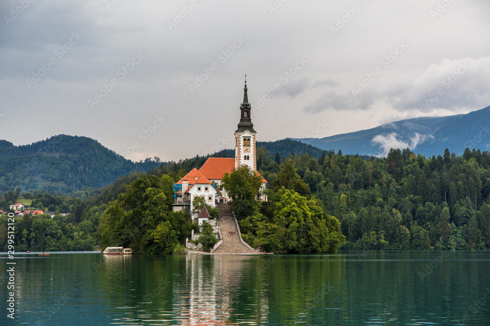 Bled, Slovenia - July, 2019: Lake Bled with St. Marys Church of Assumption on small island. Mountains and valley on background. Space for your text.