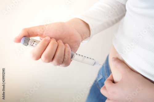 Close up of female diabetes patient making subcutaneous insulin injection into her abdomen with insulin pen syringe for at home. Diabetes, health care and medical concept. Diabetes World Day. photo