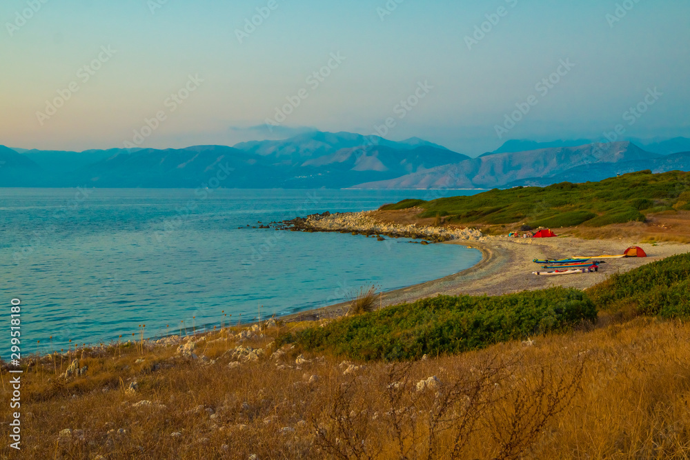 Sunset at Antinioti West Beach in Corfu Island. Tourists are relaxing in background