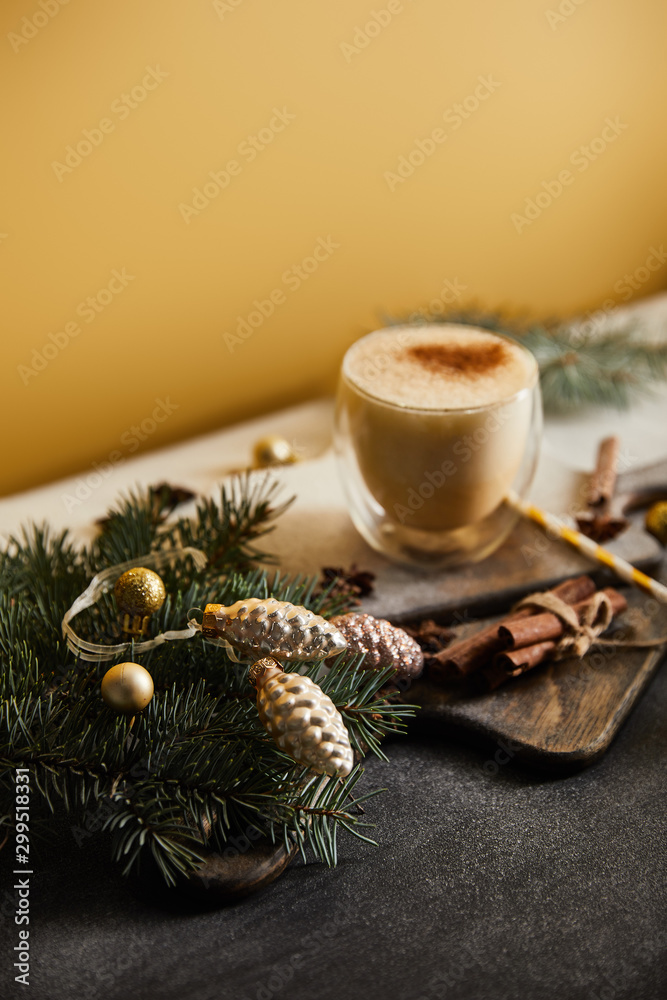 eggnog cocktail on table covered with sugar powder, spruce branches, cinnamon sticks and Christmas baubles on orange background eggnog cocktail on table covered with sugar powder, spruce branches, cinnamon sticks and Christmas baubles on orange background