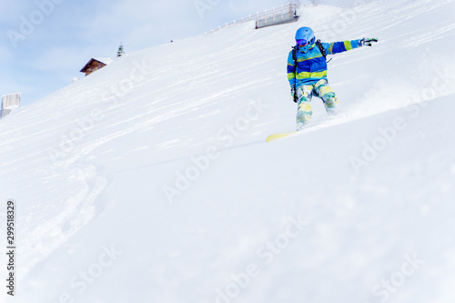 Sports male snowboarder rolling on hillside in afternoon.