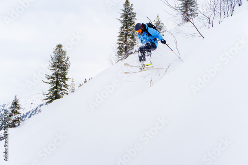 Photo of sports man with beard skiing in winter resort