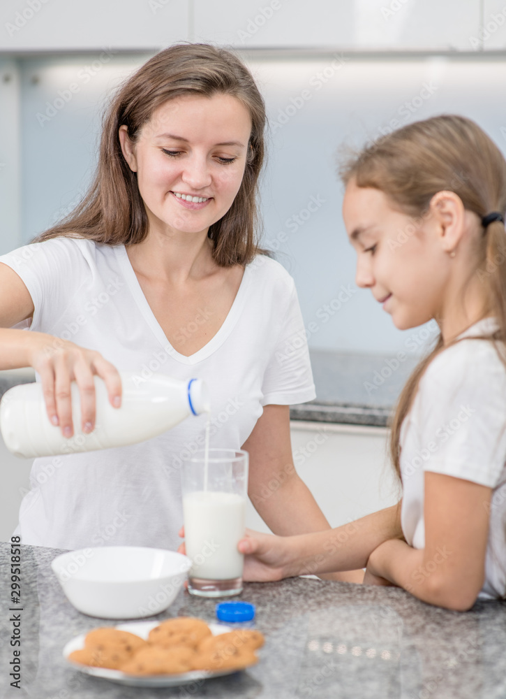 Attractive young woman and her little cute daughter eat on kitchen Attractive young woman and her little cute daughter eat on kitchen