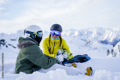 Photo of .two sports women with thermos sitting in ski resort in winter.