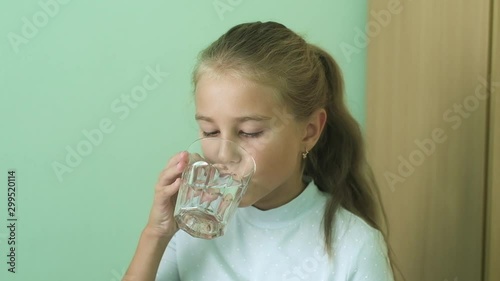the girl takes a pill in her hand and swallows it. the teenager washes down the pill with clean water in a glass. Disgusted,  sticks out his tongue. Taking drugs in the clinic.