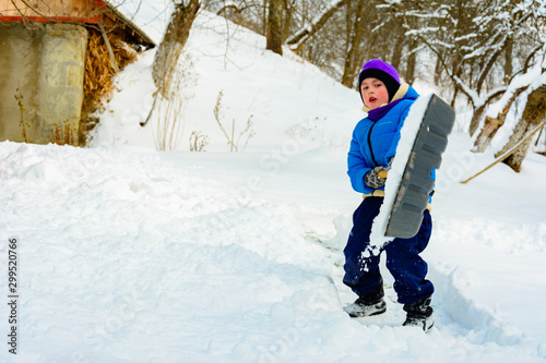 After heavy snow, the little boy clears the snow with a shovel.