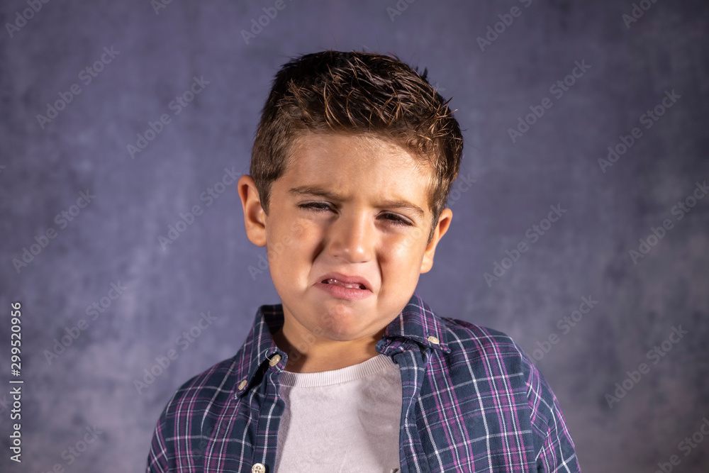 Little boy sad crying isolated in blue