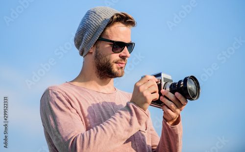 Professional photographer. Handsome photographer guy retro camera. Photojournalist concept. Guy photographer outdoors sky background. Hipster reporter taking photo. Manual settings. Travel blogger