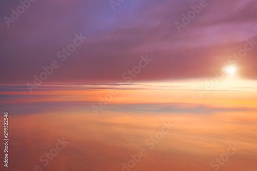 Amazing view from plane between different layers of clouds on the sky, sunrise sun. © aapsky