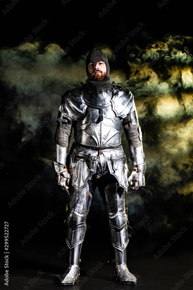 handsome knight in armor looking at camera on black background handsome knight in armor looking at camera on black background