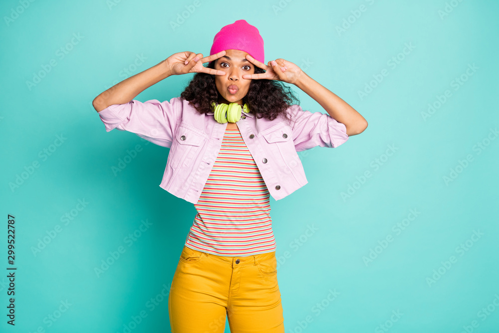 Photo of cute nice pretty casual charming sweet student teenager showing double v-sign wearing yellow trousers striped t-shirt stylish trendy isolated over teal pastel color background in cap headwear Photo of cute nice pretty casual charming sweet student teenager showing double v-sign wearing yellow trousers striped t-shirt stylish trendy isolated over teal pastel color background in cap headwear