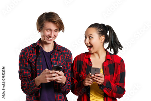 Happy young guy and girl with smartphones in hand, chatting with each other and laughing. isolated on white