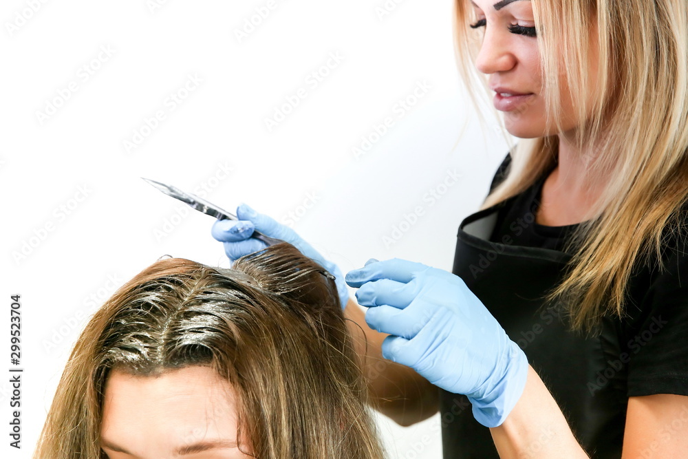 Fototapeta premium hair dyeing process in a hair salon. hair care close-up. The hands of a hairdresser in gloves make hair dyeing at the hairdresser salon. beautiful girl hairdresser works in the barber shop