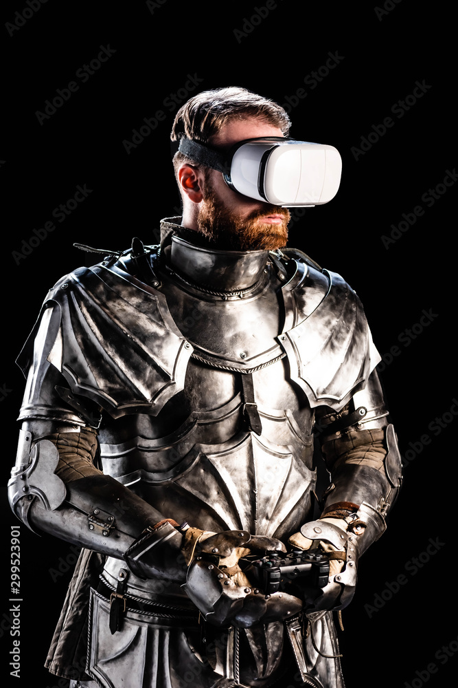 KYIV, UKRAINE - OCTOBER 9, 2019: knight with virtual reality headset in armor holding joystick on black background KYIV, UKRAINE - OCTOBER 9, 2019: knight with virtual reality headset in armor holding joystick on black background