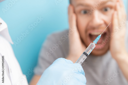 Картината върху платно Man is fear and cries from syringe with vaccination doctor appointment