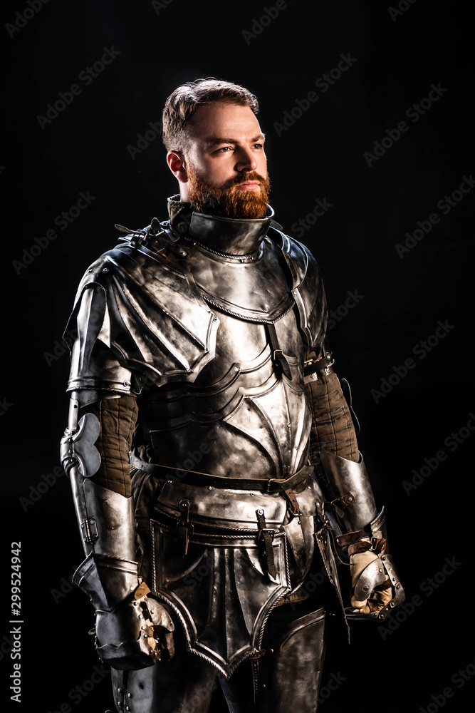 handsome knight in armor looking away isolated on black