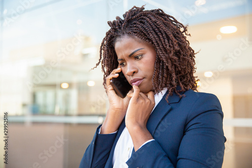 Slika na platnu Frowning concerned manager speaking on cellphone outside