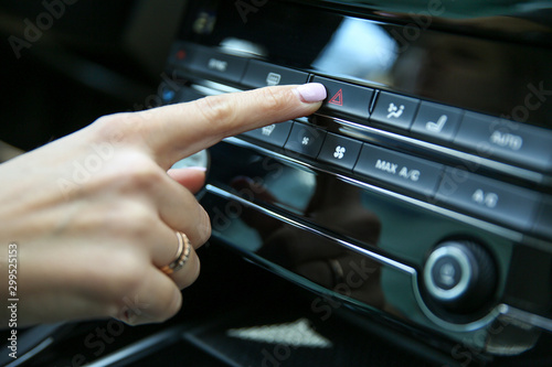 the hand of the car driver turns on the alarm. woman's hand presses the Emergency button with red triangle in the car close-up