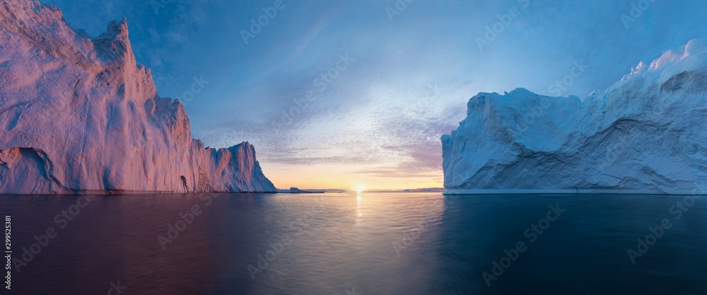 Fototapeta Early morning summer alpenglow lighting up icebergs during midnight season. Ilulissat, Greenland. Summer Midnight Sun and icebergs. Blue ice in icefjord. Affected by climate change and global warming.