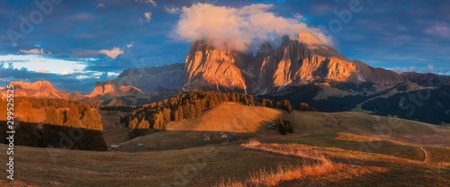 Aerial autumn sunrise scenery with yellow larches and small alpine building and Odle - Geisler mountain group on background. Alpe di Siusi (Seiser Alm), Dolomite Alps, Italy. Dolomites mountains