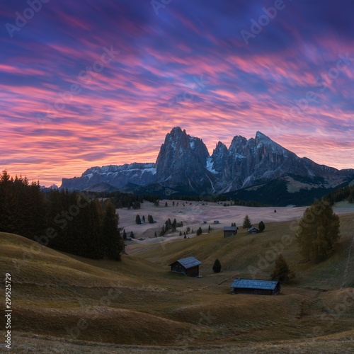Aerial autumn sunrise scenery with yellow larches and small alpine building and Odle - Geisler mountain group on background. Alpe di Siusi (Seiser Alm), Dolomite Alps, Italy. Dolomites mountains