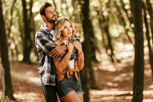 Handsome man embracing dreamy girlfriend while looking away in park © LIGHTFIELD STUDIOS