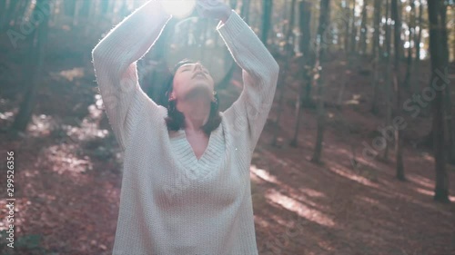 Beautiful woman is relaxing, meditating in a sunny day on forest. Falling leaves, autumn time and enjoy, purity attractive girl. Fresh with deep breathing, season and freedom concept. 