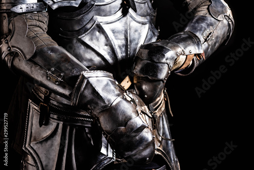 cropped view of knight in armor holding sword isolated on black © LIGHTFIELD STUDIOS