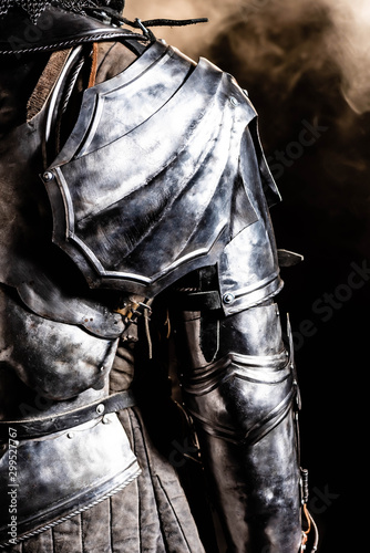 cropped view of knight in armor on black background