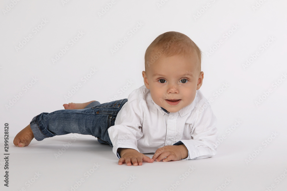 Kleines männliches Baby liegt lächelnd auf weißem Untergrund Kleines männliches Baby liegt lächelnd auf weißem Untergrund