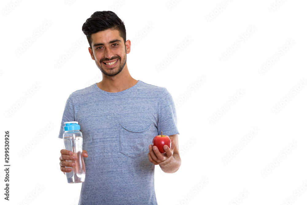 Happy Persian man smiling while holding red apple and water bottle Happy Persian man smiling while holding red apple and water bottle