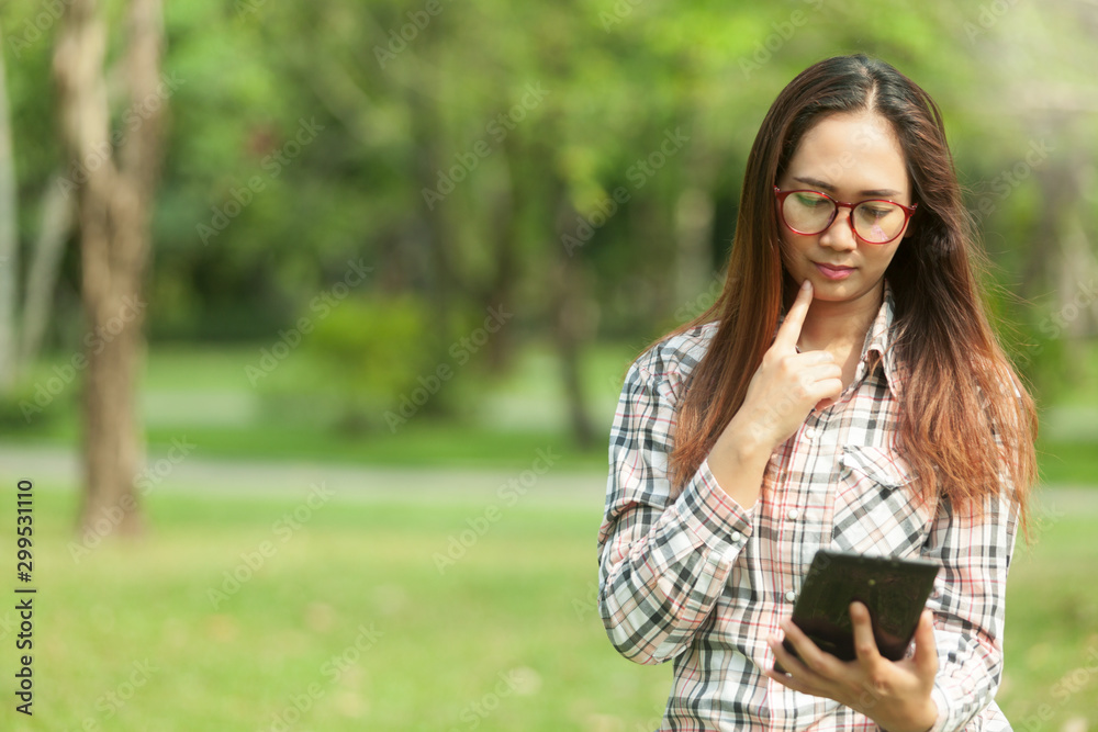 woman relaxes in the garden with reading news,check mail with a phone on a bright day woman relaxes in the garden with reading news,check mail with a phone on a bright day