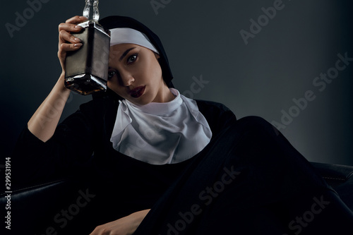 фотографія Cropped shot of a nun, sitting on a black chair