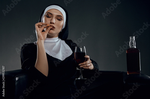 Принти на полотні Cropped half-turn shot of a nun, sitting on a black chair