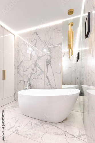 Luxury designer marble-tiled bathroom with gilded details for a cozy evening of body care and relax