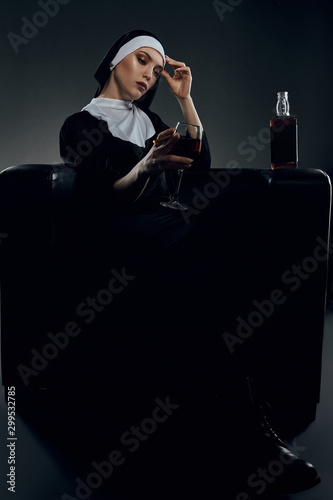 фотографія Full length shot of a nun, sitting on a chair