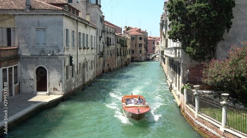 Venice, Italy - July 1, 2018: Panoramic view of Venice narrow canal with historical buildings and boats traffic from Bridge Foscari. Landscape of summer sunny day and blue sky photo