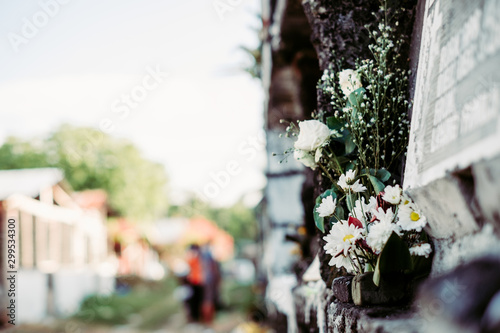 Bouquet of flowers offered or given to the dead, in one of the apartment tombstones, during a visit in the cemetery during All Souls Day. Selective focus. Copy space.