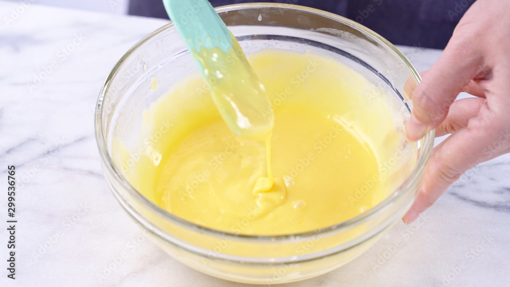 Mixing egg yolk into cake batter with green rubber spatula mixer tool stirring until smooth and blend well in a glass bowl, close up, lifestyle Mixing egg yolk into cake batter with green rubber spatula mixer tool stirring until smooth and blend well in a glass bowl, close up, lifestyle