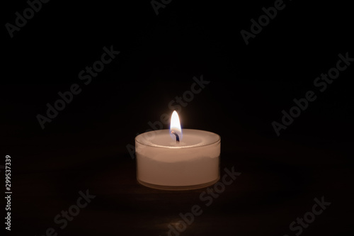 Closeup of a candle on a wooden table with dark background - middle